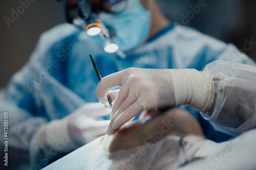 work of a surgeon in the operating room, a surgical instrument in hand.