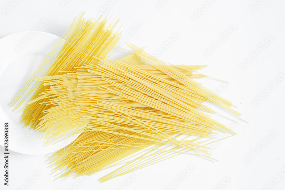 Italian durum wheat spaghetti and a round white plate on a white plate. View from above. Minimalism. Free space for recording