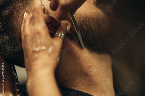 Man getting shaved with straight edge razor by hairdresser at barbershop © Zamrznuti tonovi