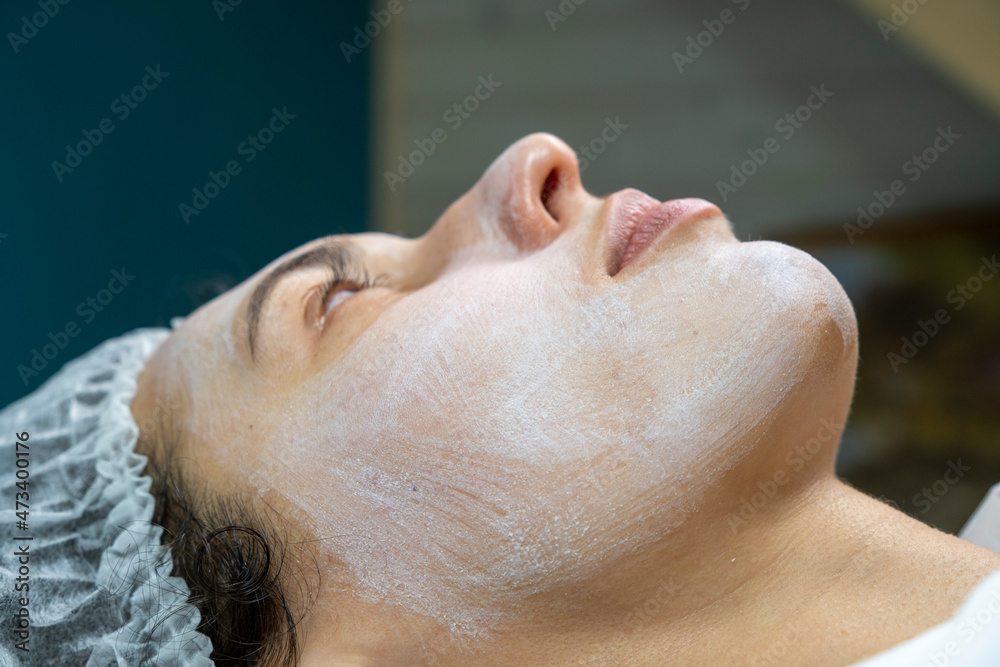 Beauty clinic concept. Young woman getting professional facial procedure. Beautician spreads mask on female face with brush. Face renovation concept. Beauty clinic concept. Young woman getting professional facial procedure. Beautician spreads mask on female face with brush. Face renovation concept.