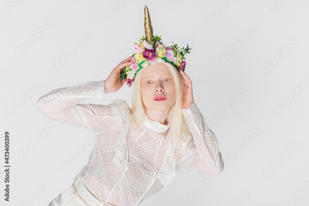 Fototapeta premium Young albino woman in wreath with flowers looking at camera isolated on white.