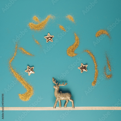 Golden reindeer ornament on a pastel blue background with glittering stars above. Minimal Christmas concept