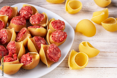 Lumaconi pasta stuffed with minced meat lies on a white plate, close-up photo