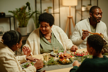 Portrait of smiling African-American grandmother celebrating Thanksgiving with big family at dinner table
