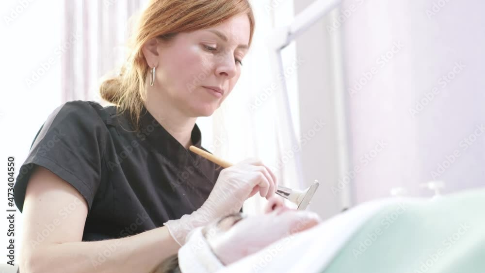 Cosmetologist applying mask with brush on young pretty woman face in beauty clinic, spa salon Cosmetologist applying mask with brush on young pretty woman face in beauty clinic, spa salon