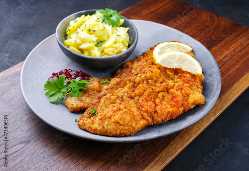 Φωτογραφία Traditional deep-fried schnitzel with potato salad, cranberries and lemon slices