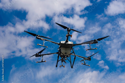 A drone-sprayer flies in the sky with clouds over the field. Smart , modernan...