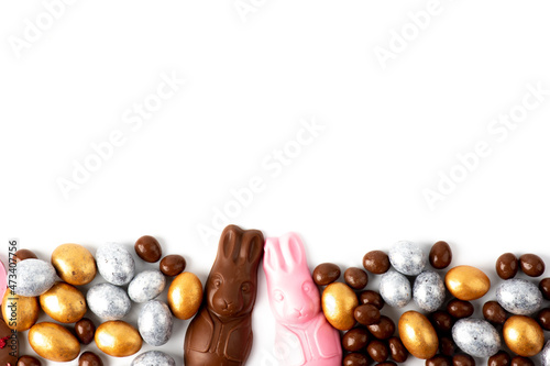 Easter bunny with chocolate eggs and candies on white background. Top view of easter composition with chocolate candies on white table with copy space