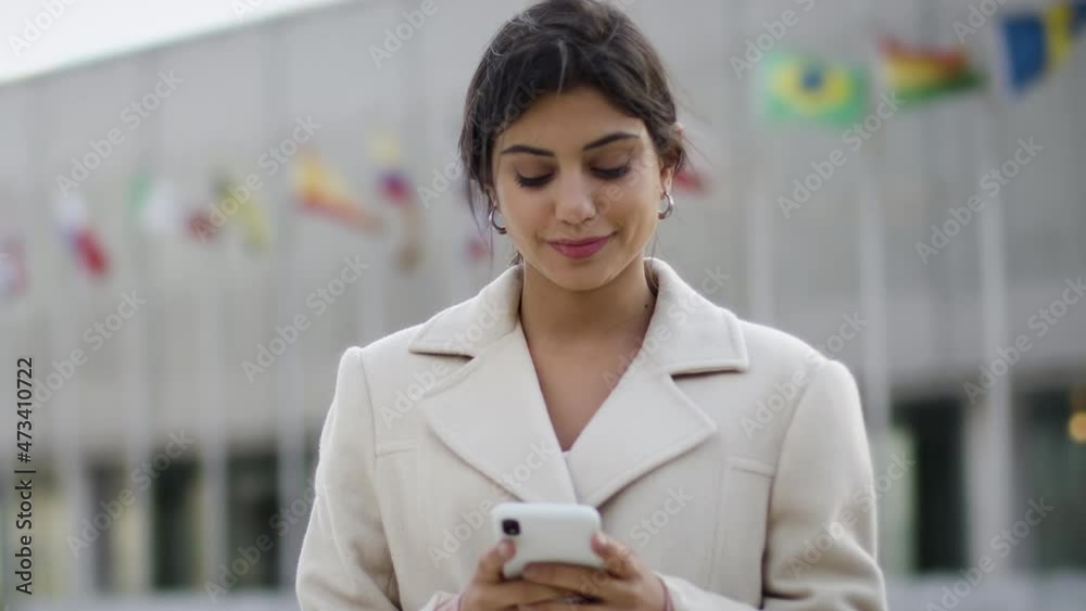 Lateral Dolly Close Up Slow Motion Successful and Cheerful Young Brunette Business Woman Using Smartphone in The City Financial District. She Is Sending Messages and Laughing. Lateral Dolly Close Up Slow Motion Successful and Cheerful Young Brunette Business Woman Using Smartphone in The City Financial District. She Is Sending Messages and Laughing.