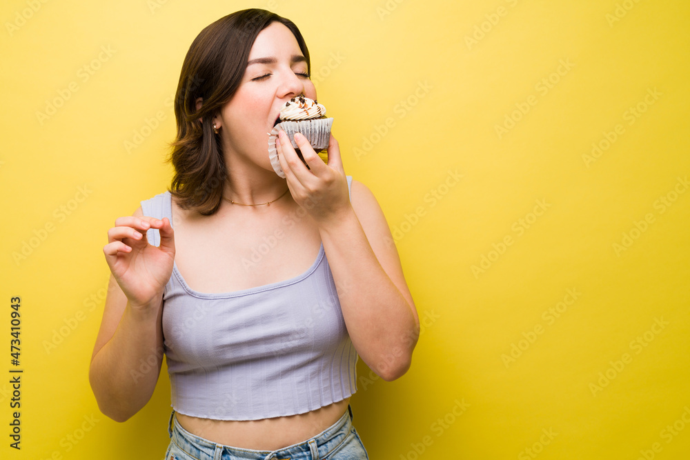Caucasian woman enjoying eating a cupcake Caucasian woman enjoying eating a cupcake