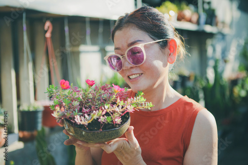 beautiful woman raising pot of blooming flower with happiness face
