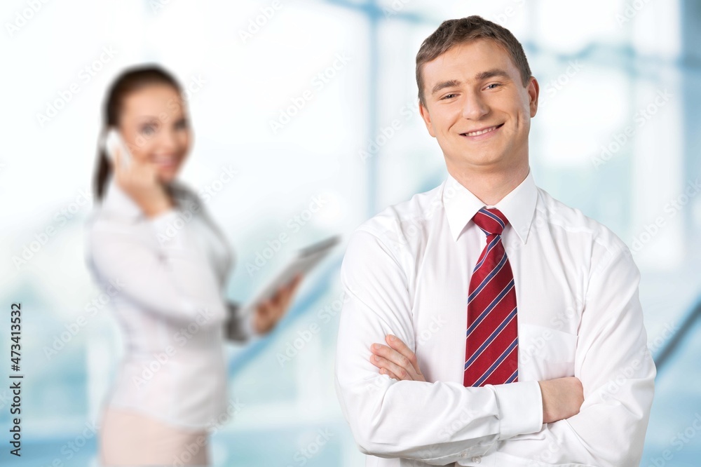 A couple of smiling business people on the office background A couple of smiling business people on the office background