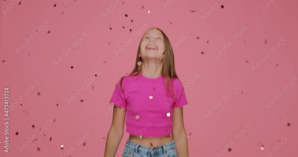 Confetti falling on happy little girl child jumping under spangles while birthday party celebration on pink background Confetti falling on happy little girl child jumping under spangles while birthday party celebration on pink background