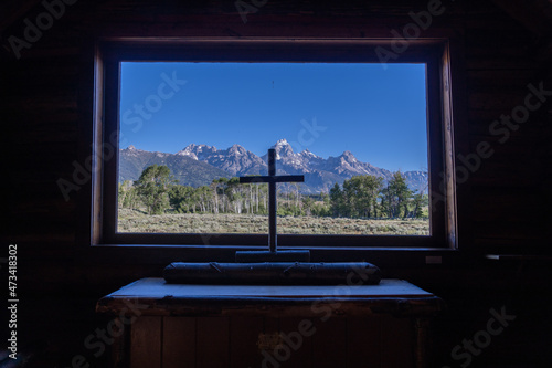 Chapel of the Transfiguration Episcopal in Grand Teton National Park, Wyoming - looking through the window at the mountains with the church cross photo