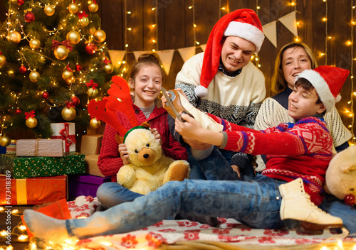 Happy family posing in new year or christmas decoration. Children and parents. Holiday lights and gifts, Christmas tree decorated with toys.