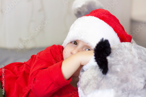Portrait of a cute boy in a Santa Claus hat. Funny smiling child. Gifts, toys, joy, celebration.