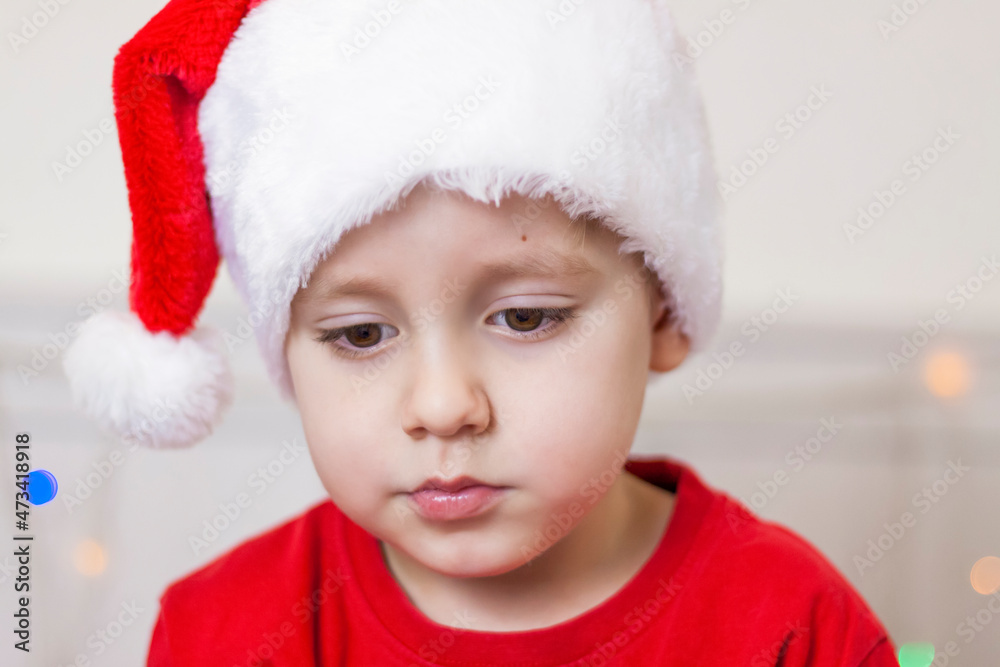 Portrait of a cute boy in a Santa Claus hat. Funny smiling child. Gifts, toys, joy, celebration. Portrait of a cute boy in a Santa Claus hat. Funny smiling child. Gifts, toys, joy, celebration.