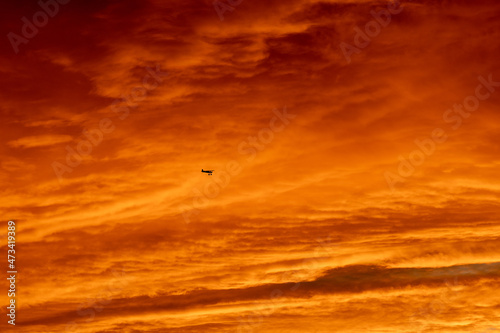 Golden sunset with airplane silhouette in front of clouds