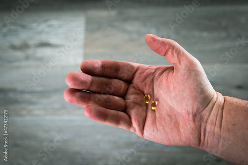 Man’s Hand Holding Vitamin Pills in the Palm