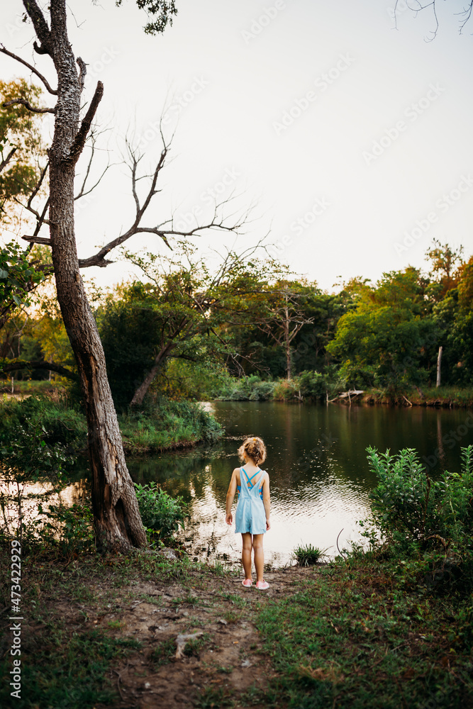 Young girl standing at edge of lake looking for fish in summer Young girl standing at edge of lake looking for fish in summer