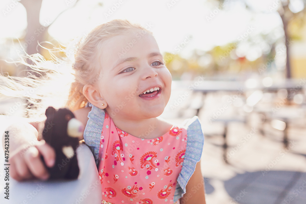 Preschooler girl holding a teddy bear playing at a park. Preschooler girl holding a teddy bear playing at a park.