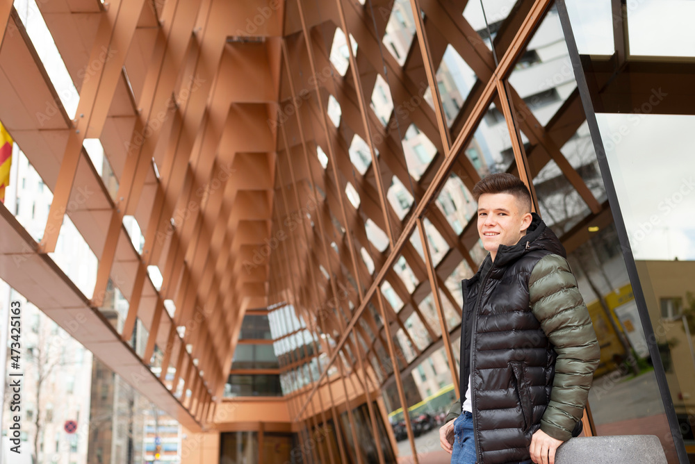 Young guy standing against modern building Young guy standing against modern building