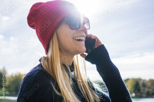 Young blonde woman in park making a phone call with happy expres photo