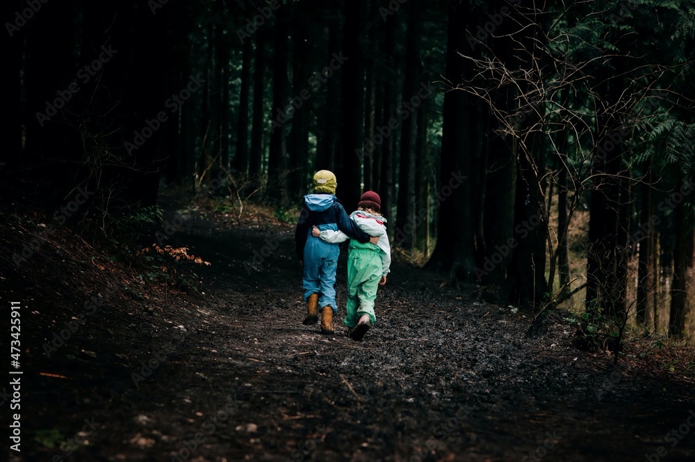 kids walking with their arms around each other into the dark forest kids walking with their arms around each other into the dark forest