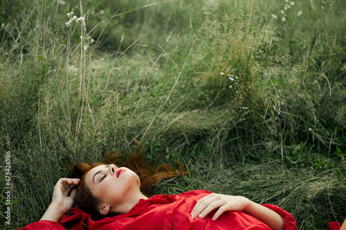 pretty woman in red dress lies on the grass freedom landscape © VICHIZH