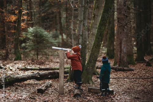 Young children in German forest exploring with telescope in winter photo