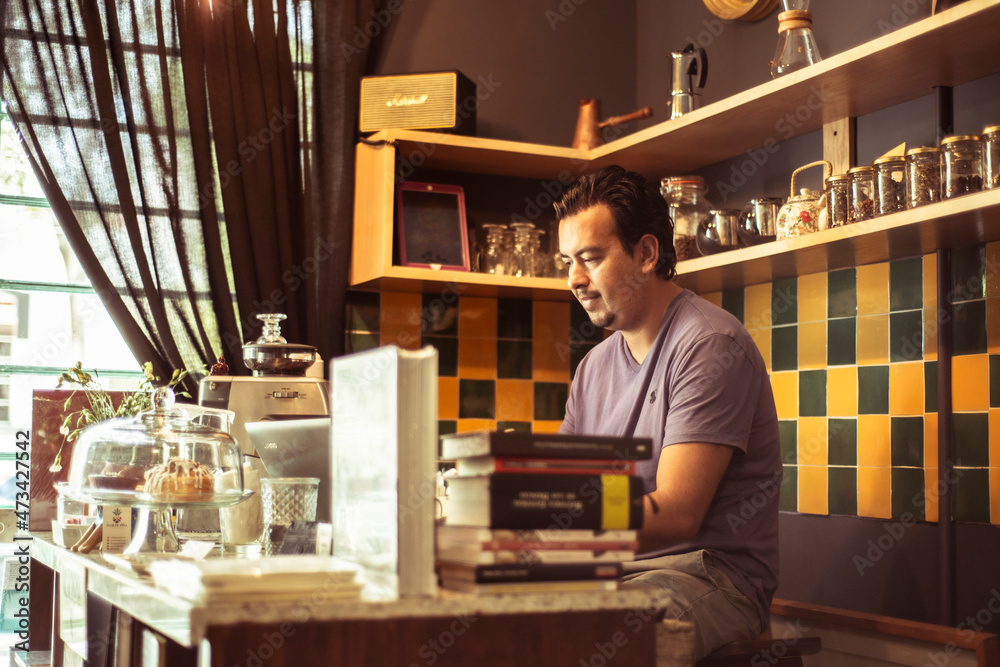 Barista at colourful cafe serving behind counter Barista at colourful cafe serving behind counter