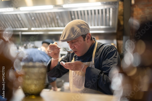 Male cook trying dish in cafe kitchen