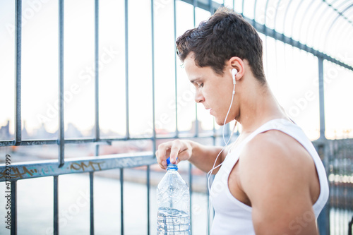 Young man resting after running while drinking water photo