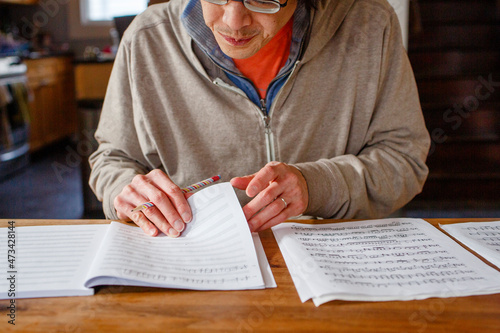 close-up of man transcribing music with pencil on paper at table photo