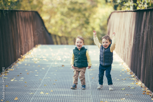 Two super positive toddler twin boys on a walk in autumn park photo