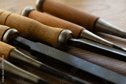 Wood carving chisels, in various sizes, on a old workbench. Shallow depth of field.