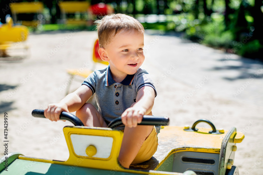 Adorable 2 years old kid riding wooden car at summer park playground Adorable 2 years old kid riding wooden car at summer park playground