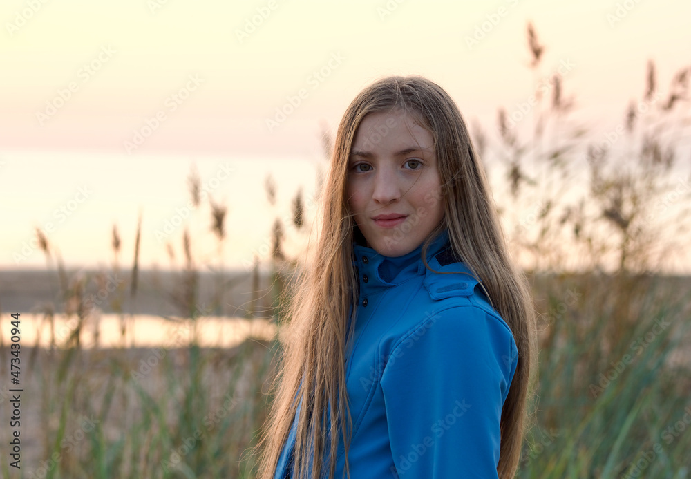 Portrait of young teen girl in hooded jacket at the beach