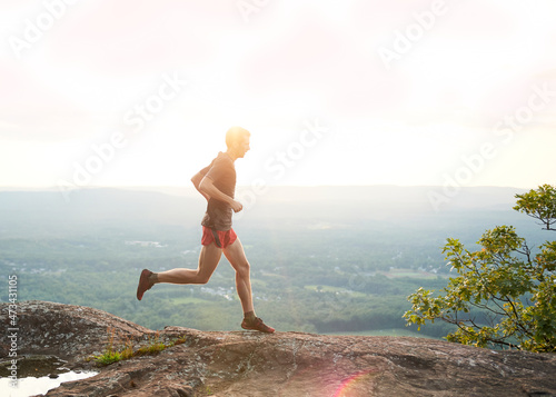 Adult male trail runner on a mountain ridge at sunset photo