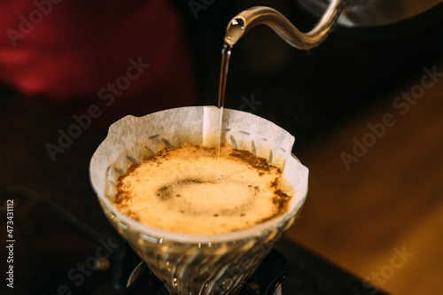 Pouring water in coffee filter at cafe photo