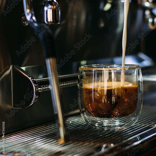 Milk pouring into a glass cup with coffee photo