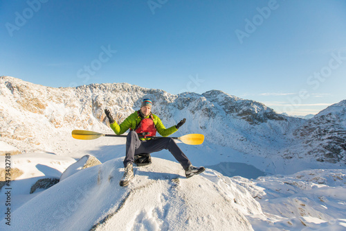 Paddler with raised arms after arriving at unexpected frozen lake.