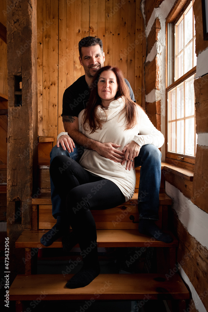 Attractive couple sitting on stairs together inside rustic log cabin. Attractive couple sitting on stairs together inside rustic log cabin.