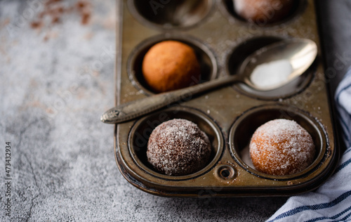 Close up of donut holes covered in sugar in a baking tin.
