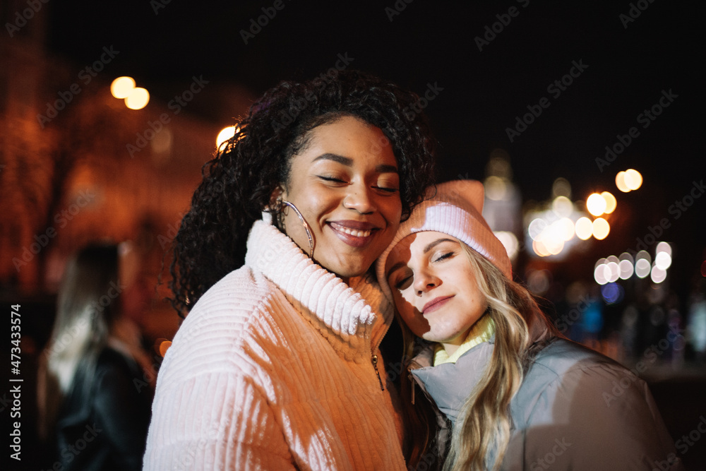 Portrait of happy girlfriends standing in city at night Portrait of happy girlfriends standing in city at night