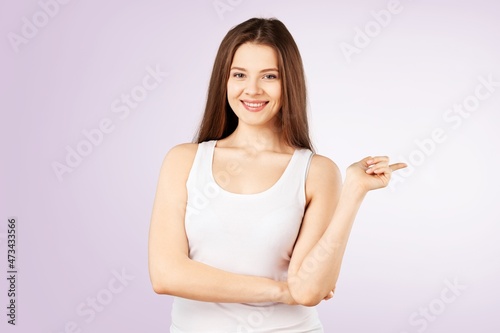 Woman showing pointing on background. Young lady smiling happy presenting © BillionPhotos.com