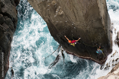 Rock climber climbs a pilar out of the ocean in Tasmania, Australia. photo