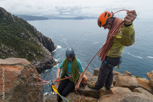 Adventurous couple has a laugh while coiling the rope as they climb the exposed sea cliffs of Cape Raoul on a cloudy day, in Tasmania, Australia. photo