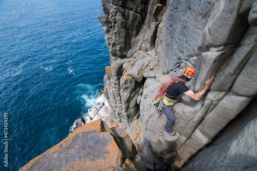 Male adventurer heads off into the unkown, armed with ropes and climbing gear, as he explores dolerite rock columns in the sea cliffs of Cape Raoul, in Tasmania, Australia. photo