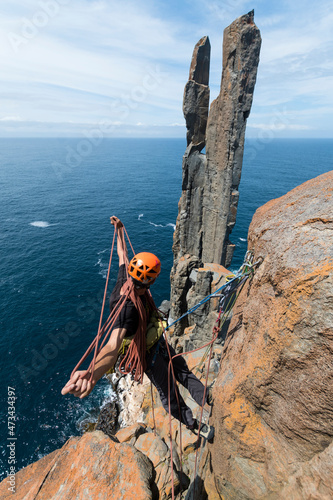 Male adventurer coils up the rope as he scopes his next challenge: two freestanding rock pilars emerging from the ocean in the sea cliffs of  Cape Raoul, in Tasmania, Australia. photo